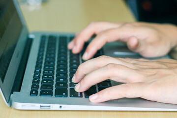 fingers typing on laptop keys, closeup side view