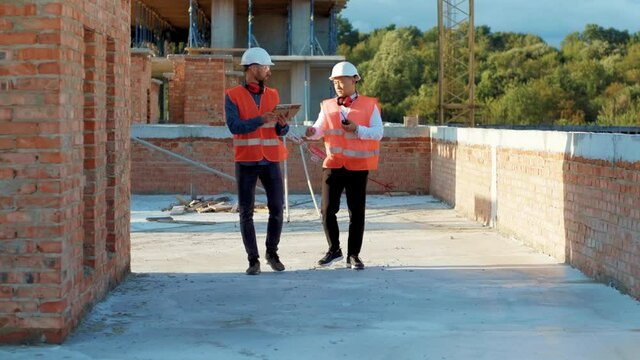 Twp men builder taking and walk through construction at sunlight survey urban meeting skyscraper architect contractor inspector construction helmet slow motion