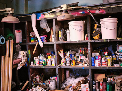 Shelves in an artists studio packed with clutter supplies and material