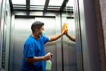 maintenance personnel disinfecting the interior of the elevator - obrazy, fototapety, plakaty