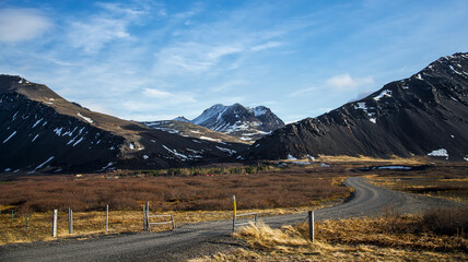 Mountain range with an orange field of grass and clouds in an Icelandic landscape