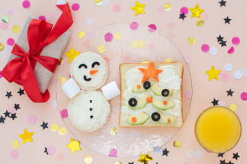 Obraz na płótnie Canvas Funny Christmas breakfast, sandwiches in the form of Christmas trees and a snowman. With branches of avocado. Flat lay