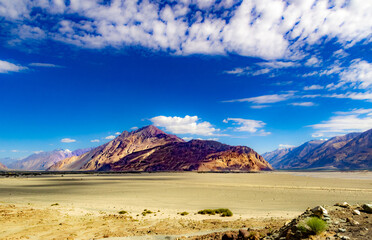 Fototapeta na wymiar High dynamic range image of barren mountain in a desert with deep blue sky and white patchy clouds in ladakh, Jammu and Kashmir, India