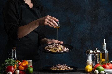 The chef in black uniform standing the left of the table and adding the honey to the tasty dish for breakfast. Cooking meal with honey for healthy life isolated on black background.