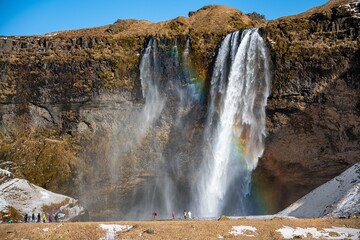 Waterfall from a cliff with a rainbow and mist in Iceland