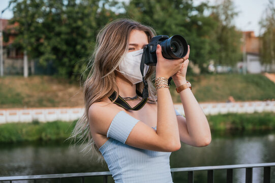 Young woman wearing mask taking pictures with her camera