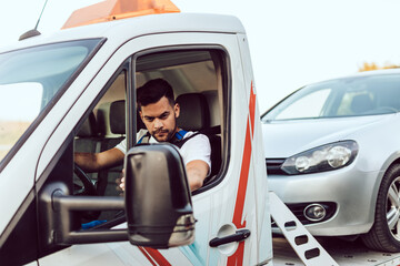 Handsome middle age man working in towing service on the road. Roadside assistance concept.