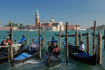 Fototapeta na wymiar Gondoliers working the Giudecca Canal in front of San Giorgio Maggiore in Venice
