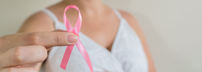 October Breast Cancer Awareness month, Woman in white dress with hand holding Pink Ribbon