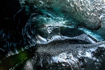 The blue abstract texture in an ice cave in Iceland with air pockets, bubbles, and dirt with rocks.