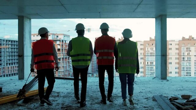 Shot back builders engineers workers in hard hat team walking on construction at sunlight survey urban meeting skyscraper builder architect contractor inspector construction helmet slow motion