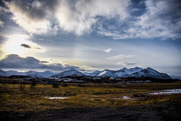 Village surrounded by mountains with white peaks in an Icelandic landscape