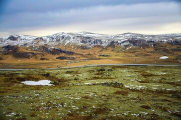 Mountains in an icelandic landscape with clouds, green moss, and orange grass