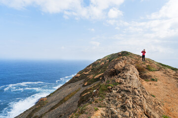 Hiker girl taking a picture in a cliff by the sea