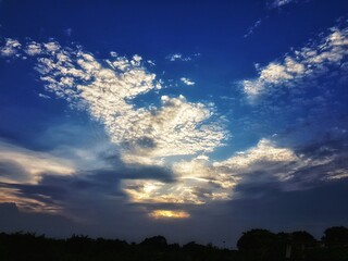 blue sky with white patchy clouds during sunset blue hour with silhouette horizon