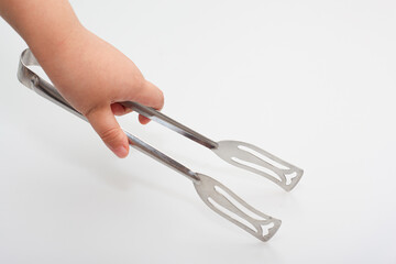 
Asian child's hand holding cooking tongs
