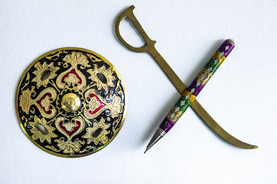 pen is mightier than sword concept by decorated round sword shield and pen in white background.antique artefact