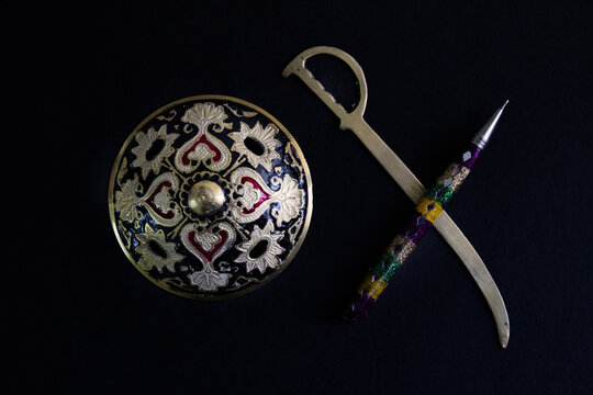 pen is mightier than sword concept by decorated round sword shield and pen in black background .antique artefact