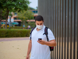 Hombre de negocios joven con mascarilla usando su movil respetando las medidas de seguridad y...