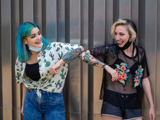 Mujeres jovenes saludandose con el codo de manera segura para respetar las medidas de seguridad y...