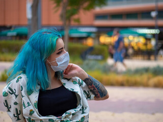 Mujer joven con los pelos de colores y tatuajes vistiendo mascarilla durante la pandemia del...