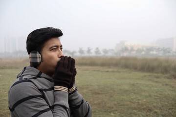 a man feeling cold being dressed in winter garments and gloves with focus on model's face with a...