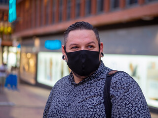 Fototapeta na wymiar Hombre joven vistiendo mascarilla durante la pandemia del coronavirus cumpliendo la normativa de seguridad del covid-19