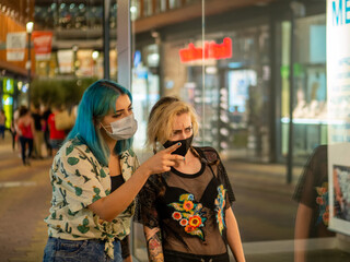 Mujeres jóvenes con mascarilla hablando respetando las medidas de seguridad y distanciamiento...
