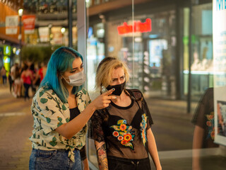 Mujeres jóvenes con mascarilla hablando respetando las medidas de seguridad y distanciamiento...