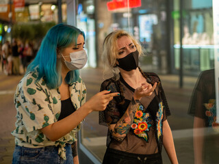 Mujeres jóvenes con mascarilla hablando respetando las medidas de seguridad y distanciamiento...