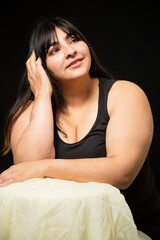 Portrait Hispanic woman smiling looking up on black background - inclusive beauty- curvy woman - body positive character, feminism, self love, beauty concept