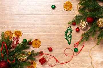 Xmas banner with deer, cone, gift box, oranges, tape, beads and Christmas tree on wooden background. Copyspace. New year top view