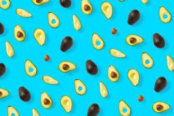 Avocado. Background made from isolated Avocado pieces on blue background. Flat lay of fresh ripe avocados and avacado pieces.