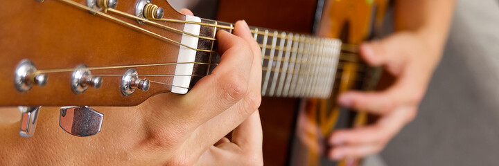 Young boy playing guitar. Close-up of man hand playing classic guitar. teenager learning playing guitar. Banner or panoramic shot.