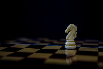 Horse chess piece on brown chessboard