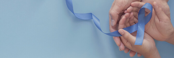 adult and child hands holding blue ribbon on blue background , Prostate Cancer Awareness, Movember...