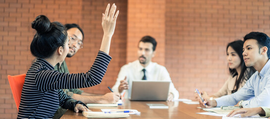 Asian office woman raising hand for asking question manager in meeting