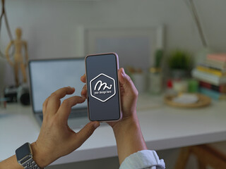 Male hand holding and touching on mock up smartphone in blurred background
