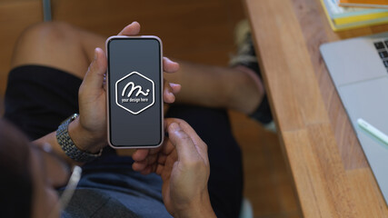 Male freelancer showing mock up smartphone while sitting worktable
