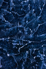 Detailed macro photo of Cracks and frozen bubbles on ice of deep lake in winter. Nature background.