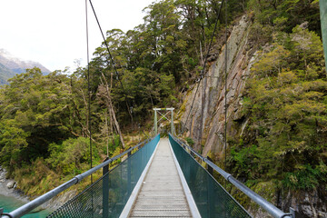 Fototapeta na wymiar Wood bridge with rope for walking in Mount Aspiring National Park, New Zealand.