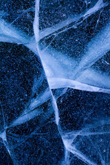 Detailed macro photo of Cracks and frozen bubbles on ice of deep lake in winter. Nature background.