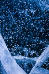 Detailed macro photo of Cracks and frozen bubbles on ice of deep lake in winter. Nature background.