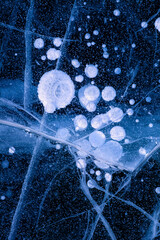 Detailed macro photo of Cracks and frozen bubbles on ice of deep lake in winter. Nature background.