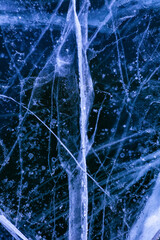 Detailed macro photo of Cracks and frozen bubbles on ice of deep lake in winter. Nature background.