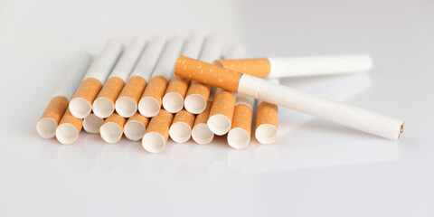 Cigarettes with a yellow filter lie on a white surface