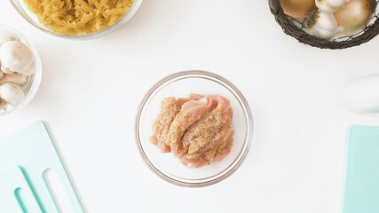 Marinated chicken fillet in a bowl, close up view from above, copy space, white background