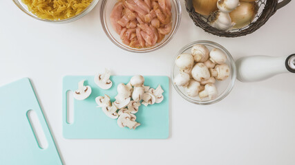 Fresh raw chopped organic white mushrooms close up on cutting board on white background, directly from above