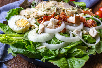One big dish of caesar salad on wood table.