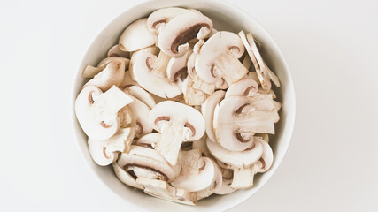 Bowl of fresh row chopped mushrooms close up on whiite background, flat lay